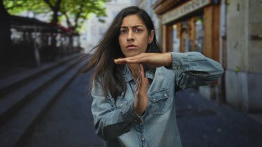 Kadın, şehir caddesinde merdivenlerin ve mağazaların yakınındaki kot gömlekli el ve avuçlarıyla mola jesti yapıyor; sınır çizme hüsranı.