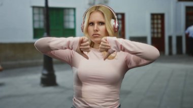 Kulaklıklı bir kadın şehir sokaklarında sarı saçlı ve pembe elbiseli bir kadın şehir ortamında hayal kırıklığı ya da anlaşmazlık gösteriyor..