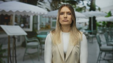 Şehir kafesindeki terasta oturan bir kadın zarif bir restoranın ortasında düşünceli bir ifadeyle..