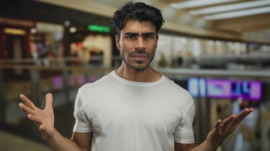 Beyaz tişörtlü, elleri bulanık dükkanlar tarafından kaldırılan ve alışveriş merkezinde cam parmaklıklar olan bir adam..