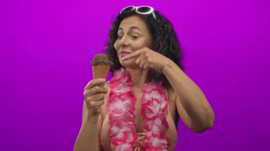 Orta yaşlı İspanyol kadın elinde dondurma külahı tutuyor ve stüdyoda kabul, eğlence, yaz, keyif tabelası yapıyor..