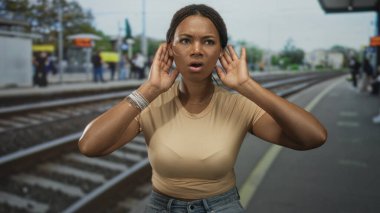 Tren peronunda rayların yanında kulaklarını tıkırdatan genç bir kadın raylara bakarken acil bir durum söz konusu..