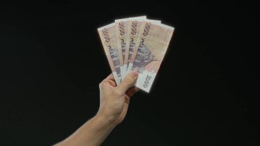 İzlanda Krona banknotları tutan adam siyah bir arkaplan üzerinde, izole bir ortamda İzlanda parası sergiliyor, finans veya para birimi teması için mükemmel.