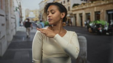 Kadın, park halindeki scooterların ve binaların yakınındaki bir sokakta omuz omuza dokunuyor. Kendine güven..