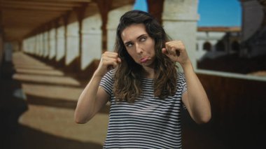 İspanyol kadın, güneş ışığı altında eski şehir sokağında gevşek dudaklı yumruklarıyla ellerini kaldırıyor..