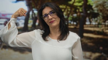 Kadın, ağaçların arasından süzülen yumuşak güneş ışığıyla gür ormanda kaslarını esnetir; güçlendirme.