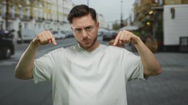 Beyaz tişörtlü genç adam kalabalık bir şehir caddesini işaret ediyor. Açık hava Avrupa ortamında şehir enerjisini ve modern yaşam tarzını yakalıyor..