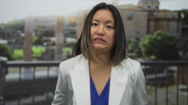 İfadesi belirsiz bir kadın antik Roma harabelerinin önünde duruyor, beyaz spor ceket giyiyor, modernlik ve tarihsel zemin arasındaki ilginç zıtlığı somutlaştırıyor..