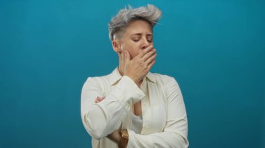 Stüdyoda eli ağızında esneyen kısa gri saçlı, yorgun ve bitkin beyaz bir kadın..