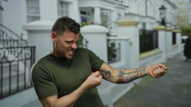 Şehir sokağında genç bir adam görünmez bir ip çekiyor ve kolunda şehir dışında görülebilen bir dövme var.