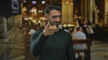 Genç adam sabah ayini sırasında dekoratif kilise binasında kamerayı işaret ediyor. Umut ışığı..