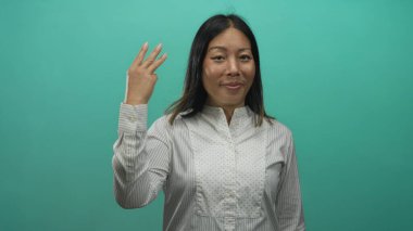 Kadın, gülümseyen ve hareket eden saçlar arasında bir stüdyoda el sallayarak barış işareti gösteriyor; sevinç kutlaması.