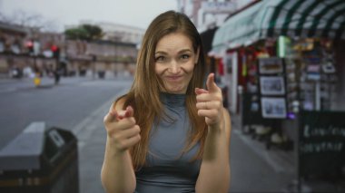 Kafkasyalı genç bir kadın canlı şehir caddesinde iki parmağını doğrudan kameraya doğrultuyor..