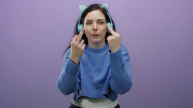 Kulaklıklı esmer kadın orta parmaklı, neşeli bir jest yapıyor, canlı mor bir arka plana gülümsüyor, mizah ve meydan okumaya karşı..