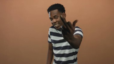 Adam stüdyoda kameraya orta parmak fiske vurur geniş bir gülümseme ve düz duruş ile ayakta durarak; cesur meydan okuma.