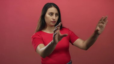 Kırmızı arkaplan, işaret parmağı ve kırmızı gömlek giyen ve kolunu kaldırmış bir kadın stüdyoda ileri doğru işaret ediyor..