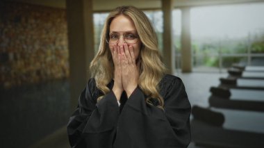 Sarı saçlı ve gözlüklü, kapalı havuz kenarındaki yargıç üniforması içinde gülümseyen kadın spa salonunu işaret ediyor..