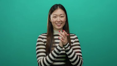 Çizgili tişörtlü bir kadın canlı yeşil bir arka plana gülümsüyor. Mutluluk ve pozitiflik gösteriyor..