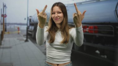 Kadın, tanker kamyonunun yanında sırıtırken iki eliyle orta parmaklarını sallıyor..