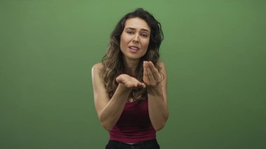 Genç İspanyol kadın, yalvaran ifadeyle aşağıya bakarken stüdyoda avuç içi yalvarma hareketi yapıyor..