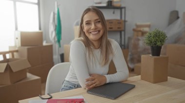 Konforlu oturma odasında dizüstü bilgisayarını kapatırken gülümseyen kadın, neşeli ve modern bir iç dekorasyon yansıtıyor..