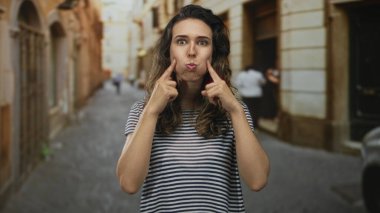 Güneşli, eski bir kasaba caddesine parmaklarını uzatan kadın tuhaf bir ifadeyle, şakacı bir yaramazlık yapıyor..