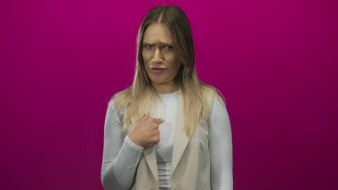 Pembe arka planda kendisine jestler yapan uzun sarı saçlı, bej ve beyaz elbiseli bir kadın, inkar ve şaşkınlığını dile getiriyor..