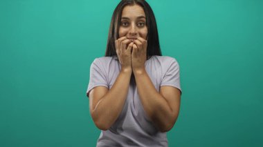 Latin kökenli genç bir kadın, açık mor t-shirt 'lü, elleri ve elleri deniz mavisi stüdyosunda tırnak yiyor..