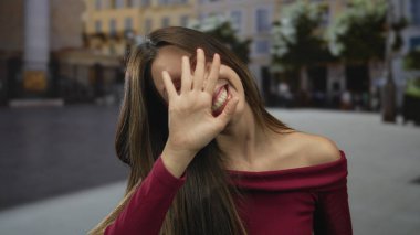 Genç İspanyol kadın kalabalık şehir caddesinde el sallıyor. Geniş bir gülümseme ve neşeli bir jest ile. Mutluluk..