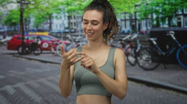 Latin kökenli genç bir kadın, şehir caddesinde bisiklet kuyruğunda el ele vererek işaret işareti yapıyor..