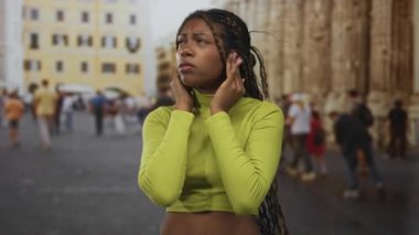 Tarihi bina ile eski kasaba caddesinde elleri kulaklarına kadar uzanan yeşil mahsullü Afrikalı Amerikalı kadın..