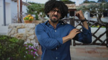 Erkekler, saksı çiçeklerinin yanındaki bina girişinde kollarını ve kollarını bükerek mavi bir gömlek ve yuvarlak bardaklar içinde gülümserler; kendinden emin bir kutlama.