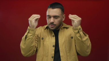 Sarı ceket giyen İspanyol genç adam kırmızı stüdyoda elini kaldırdı ve ağzını açtı..