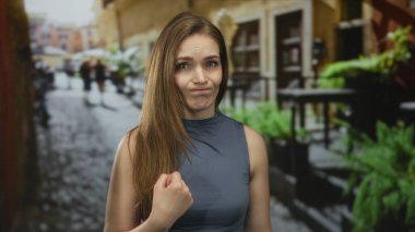 Kolsuz üst baş giyen kadın tiksindirici yüz ifadesiyle başparmağıyla şehir caddesine gidiyor..