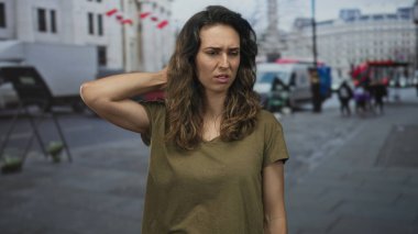 Genç İspanyol kadın kalabalık şehir caddesinde çıplak koluyla boyuna dokunuyor, bulanık araçlar ve binalar arasında kaşlarını çatıyor; acı verici..