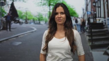 Genç İspanyol kadın elini kaldırıyor ve şüpheli görünürken bir şehir caddesini işaret ediyor; şüphecilik.