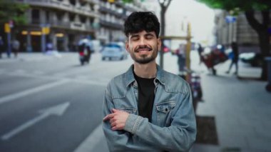 Kentsel bir sokakta kot ceket giymiş genç bir adam, kalabalık bir şehir manzarasında kendine güvenerek gülümsüyor, açık havada modern bir yaşam tarzını öneriyor..
