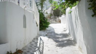 Mykonos güneşli beyazlatılmış arka planı yumuşak bokeh geçidiyle bulanıklaştırdı; arkaplan telif alanı sakin.