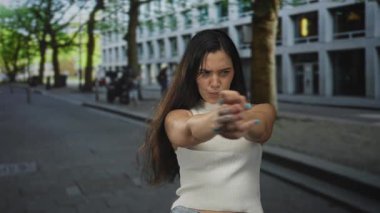 Beyaz göğüs zırhlı genç İspanyol kadın. Meşgul şehir caddesinde parmak uçlarında çıplak kol ve parmak hareketleriyle kameraya işaret ediyor. Oyuncu meydan okuma..