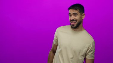 Genç adam canlı pembe duvara karşı neşeli bir ifade sergiliyor, çekici bir gülümsemeyle genç karizması ve doğallığı somutlaştırıyor..