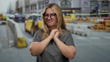 İnşaat alanında belirsizlikle el kol hareketi yapan, yoğun trafik ve belediye binalarıyla çevrili bir kadın.