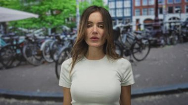 Beyaz tişörtlü genç İspanyol kadın şehir sokaklarında çıplak elleriyle orta parmaklarını sallıyor..