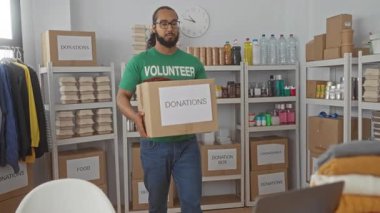 Bağış merkezinde gönüllü gömleği olan bir adam bağış kutusunu taşıyor. Merhamet servisi..