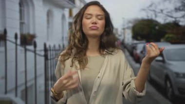 Genç, gülümseyen bir kadın hayali bir gitarı coşkuyla bir şehir caddesinde tıngırdatıyor; oyuncu yaratıcılık.