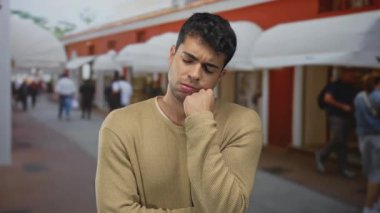 Kalabalık bir sokakta, açık havada genç bir erkek grupla uykulu ve uyuşuk hisseden bir adam kafa kafaya gidiyor..