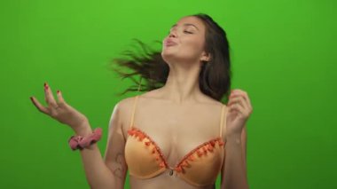 Canlı yeşil bir arka planda mayoyla poz veren kadın, gençlik enerjisi ve yaz atmosferi sergiliyor..