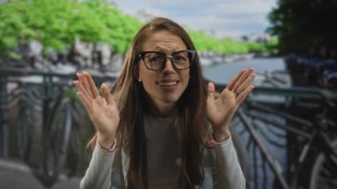 Bir kadın kulaklarına sarılıyor ve Amsterdam Köprüsü 'nde kanalın kenarında irkiliyor..