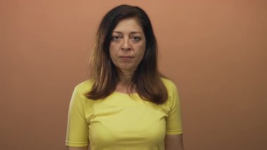 Şeftali stüdyosundaki kadın sert bir ifadeyle kamerayı işaret ediyor; sıkı komuta otoritesi aciliyeti.