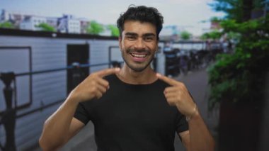 Parmakla gösterilen ve parmaklıklarla dolu kalabalık bir caddede geniş bir gülümseme; mutluluk..