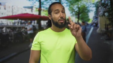 İşlek bir caddedeki açık hava restoranının terasında konuşurken adam parmağını yukarı kaldırır; güven talimatı.